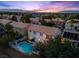 Stunning aerial view of a home with a backyard pool, lush landscaping, and city views at sunset at 2445 Antler Point Dr, Henderson, NV 89074