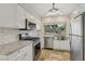 Bright kitchen with stainless steel appliances, farm sink, white cabinets, and stone countertops at 3177 Bel Air Dr, Las Vegas, NV 89109
