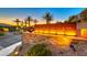 Illuminated Regatta Heights community entrance with stone wall and palm trees at 35 Via Rizzuto, Henderson, NV 89011