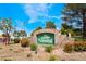 Community entrance sign for Los Verdes featuring stone architecture, lush greenery, and an American flag at 4869 S Torrey Pines Dr # 101, Las Vegas, NV 89103