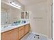 Bathroom featuring double sinks with wood cabinets, a large mirror, and a walk-in shower with a glass door at 4920 River Splash Ave, Las Vegas, NV 89131