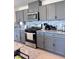 Updated kitchen featuring gray cabinets, stainless steel appliances, granite countertops, and stylish backsplash tiles at 4993 Birchland Manor Ave, Las Vegas, NV 89139