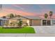 Charming single-story home featuring a lush green lawn, mature palm trees, and an inviting front entrance at sunset at 5001 Morris St, Las Vegas, NV 89122