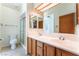Bright bathroom with a dual sink vanity, framed mirror, and tiled shower with glass door at 5029 Pacific Grove Dr, Las Vegas, NV 89130