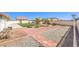 Beautifully landscaped backyard with brick pathway, gravel areas, and a white fence at 5231 E Chasemoor St, Pahrump, NV 89061