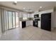 Well-lit kitchen featuring white cabinets, black appliances, tile floors, and sliding door to patio at 5271 Aurora Beam Ave, Las Vegas, NV 89122