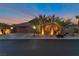 Charming home exterior at dusk featuring a three-car garage and lush palm tree landscaping at 6012 Chessington Ave, Las Vegas, NV 89131
