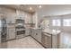 Well-lit kitchen features stainless appliances, granite countertops, tile floors and grey cabinets at 7477 Onyx Star St, North Las Vegas, NV 89084