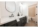 Modern bathroom with dual sinks, dark cabinets, sleek fixtures, and a view into a tiled shower/bath at 7695 Silver Wells Rd, Las Vegas, NV 89149