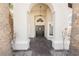 Elegant front entrance with a decorative door and stone accents, flanked by palm trees at 7695 Silver Wells Rd, Las Vegas, NV 89149