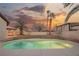Inviting pool area with lush landscaping, palm trees, and a beautiful sunset backdrop at 7695 Silver Wells Rd, Las Vegas, NV 89149