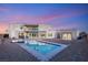 Modern backyard with a pool and spa, set against a backdrop of a stunning contemporary home at dusk at 9780 Solar Ave, Las Vegas, NV 89149