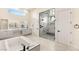 Bright bathroom featuring a luxurious soaking tub and glass-enclosed shower with bench seating at 9780 Solar Ave, Las Vegas, NV 89149