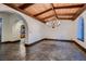 Dining area with stone floors, wooden beam ceilings, chandelier, and arched doorway at 1 Quail Run Rd, Henderson, NV 89014
