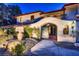 Close-up of the grand arched entryway, wrought-iron gates, and landscaped surroundings at 1 Quail Run Rd, Henderson, NV 89014