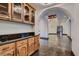 Hallway with wood cabinets, granite countertops, stone floors, and arched doorways at 1 Quail Run Rd, Henderson, NV 89014