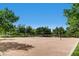 View of community sand volleyball court surrounded by lush trees with net at 1 Quail Run Rd, Henderson, NV 89014