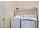 Bright laundry room with modern, white washer and dryer and upper shelf space at 1252 N Sloan Ln, Las Vegas, NV 89110
