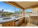 Outdoor kitchen featuring a built-in grill, marble countertops, and an open view of the pool area at 1547 Harwood Ave, Henderson, NV 89012