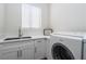 Bright laundry area with a sink, white cabinets, and a modern front-loading Bosch washing machine at 1624 Preston Park Dr, Henderson, NV 89052