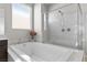 This bathroom showcases a luxurious soaking tub with a shower that features beautiful marble-look walls at 18 Via Tiberina, Henderson, NV 89011