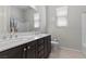 Bathroom featuring a double sink vanity with dark cabinets, a large mirror, and a separate toilet area at 18 Via Tiberina, Henderson, NV 89011