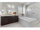 Bright bathroom showcasing a soaking tub, glass shower, dark cabinets, and tile flooring at 18 Via Tiberina, Henderson, NV 89011
