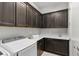 Functional laundry room with dark wood cabinets, sink, and modern front loading washing machine at 18 Via Tiberina, Henderson, NV 89011