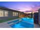 Sparkling pool with waterfall feature and artificial turf in the backyard set against a dusk sky at 18 Via Tiberina, Henderson, NV 89011