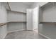 Large walk-in closet with white walls, gray herringbone floors, wooden rods, shelving, and a doorway leading to another room at 18 Via Tiberina, Henderson, NV 89011