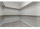 A walk-in closet with white walls and gray herringbone floors, offering ample storage space with wooden rods and shelving at 18 Via Tiberina, Henderson, NV 89011