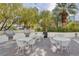 Outdoor kitchen with stainless steel grills and white tables and chairs surrounded by palm trees and greenery at 222 Karen Ave # 1804, Las Vegas, NV 89109