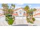 Stunning two-story home featuring a red tile roof, three-car garage, and lush landscaping with palm trees at 2608 Sun Reef Rd, Las Vegas, NV 89128