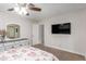 This bedroom features carpet, a TV, ceiling fan, mirrored closet, and modern dresser with decor at 2645 Heritage Ct, Las Vegas, NV 89121