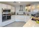 Corner view of bright, modern kitchen with stainless steel appliances, white cabinets, and marble backsplash at 2649 Golden Sands Dr, Las Vegas, NV 89128