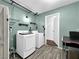 Well-lit laundry room with washer, dryer, shelving, and wood-look floors create a functional space at 2761 Phoenix St, Las Vegas, NV 89121