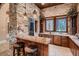 Entertainer's bar area with stone accents, custom cabinets, wine cooler, and countertop seating at 2845 Red Arrow Dr, Las Vegas, NV 89135