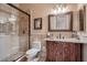 Bathroom featuring a tiled shower with glass doors, decorative mirror, and custom vanity at 2845 Red Arrow Dr, Las Vegas, NV 89135