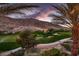 Picturesque view of a manicured golf course with mountain backdrop and desert landscaping, framed by palm trees at 2845 Red Arrow Dr, Las Vegas, NV 89135