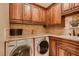 Laundry room with wooden cabinets, tile backsplash, countertops, washer, and dryer at 2845 Red Arrow Dr, Las Vegas, NV 89135