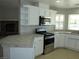 Open concept kitchen with stainless steel appliances, white cabinets, and tile countertops, perfect for modern living at 3020 Peggy Ave, Pahrump, NV 89048