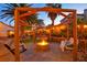 Outdoor patio area with a fire pit, swing seating, lush garden, and ambient lighting at 4517 Inez Dr, Las Vegas, NV 89130