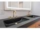 Bathroom featuring double sink vanity with black countertops, contemporary gold faucets, and a lighted mirror at 6405 Strongbow Dr, Las Vegas, NV 89156