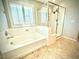 Well-lit bathroom featuring a soaking tub with white tile surround and separate glass shower enclosure at 6639 Ivory Dove Ct, Las Vegas, NV 89148