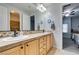 Bright bathroom featuring double sinks, light wood cabinets, and tile countertops and floors at 7256 Bugler Swan Way, North Las Vegas, NV 89084