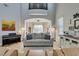 Bright, open living room featuring a vaulted ceiling, piano, large sofa, and arched entryway to the dining area at 7256 Bugler Swan Way, North Las Vegas, NV 89084