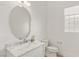 Powder room featuring a large oval mirror and modern marble vanity at 9228 Whitekirk Pl, Las Vegas, NV 89145