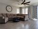 Open living room with large sectional sofa, wood floors, ceiling fan, and natural light at 9509 Arrowhead Falls Ct, Las Vegas, NV 89148