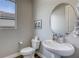 A half bath featuring a pedestal sink, toilet, and a stylish round mirror, complimented by modern fixtures at 11137 Black Fire Opal Dr, Las Vegas, NV 89138