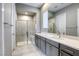 This bathroom has a walk-in shower with glass doors, bench, white counter tops and gray cabinets at 11137 Black Fire Opal Dr, Las Vegas, NV 89138